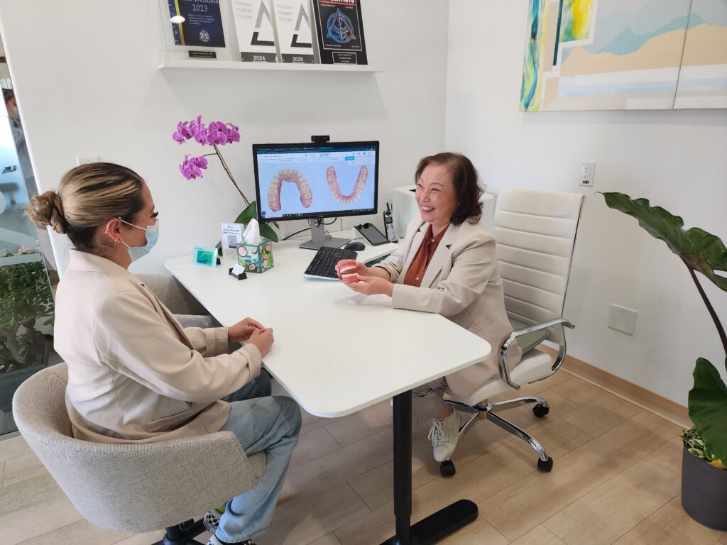 A dentist at Wellbeing Dentistry in Santa Clara, CA, demonstrating the benefits of BPA-free, biocompatible composite fillings during a patient consultation.
