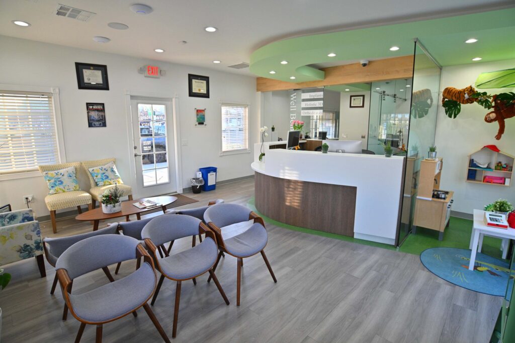 The bright, modern, and welcoming reception area of Well Being Dentistry in Santa Clara, CA, featuring comfortable seating, a clean front desk, and a dedicated play area for children.