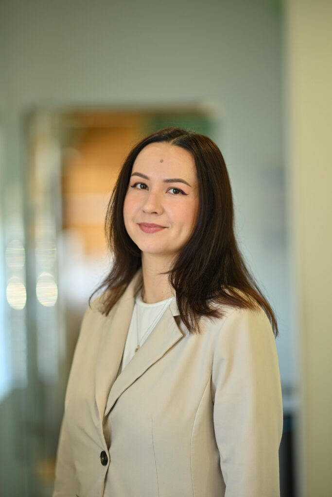 Professional headshot of Daria Rios, smiling gently in a beige blazer at Wellbeing Dentistry.