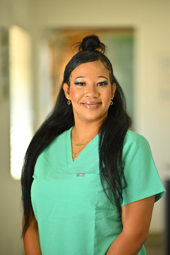 Professional headshot of Michalea Vandyke, smiling confidently in green scrubs at Wellbeing Dentistry.
