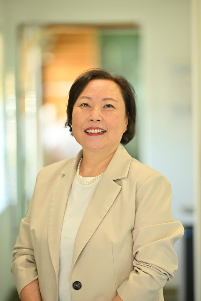 Professional headshot of Monica Pak, smiling confidently in a beige blazer at Wellbeing Dentistry.