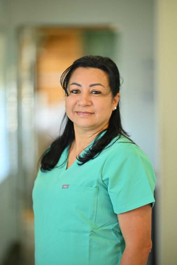 Professional headshot of Soraya Perez, smiling warmly in green scrubs at Wellbeing Dentistry.
